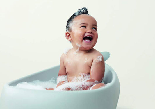 laughing baby in a bathtub with soapy water suds